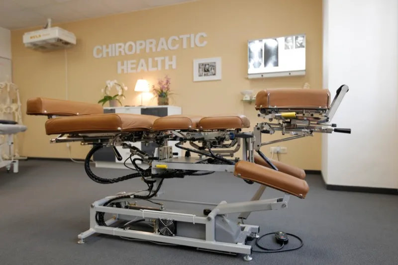 Behandlungsraum mit Cox-Liege vor dem Schriftzug „Chiropractic Health"