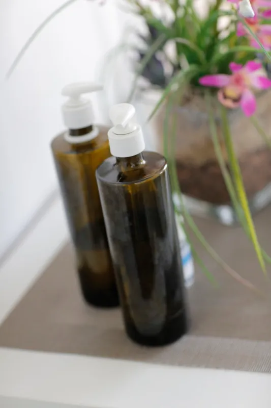 Massageöle auf einer Ablage neben Blumen