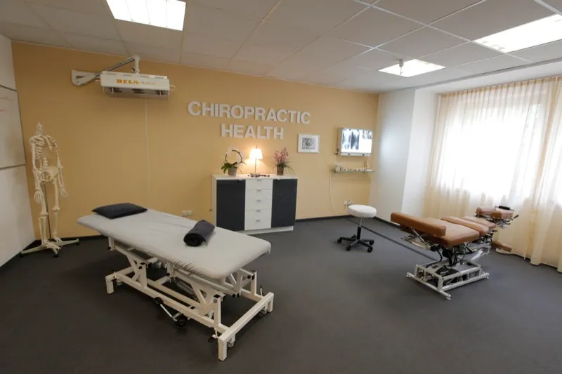 Behandlungsraum mit Liege, Skelettmodell und dem Schriftzug „Chiropractic Health"