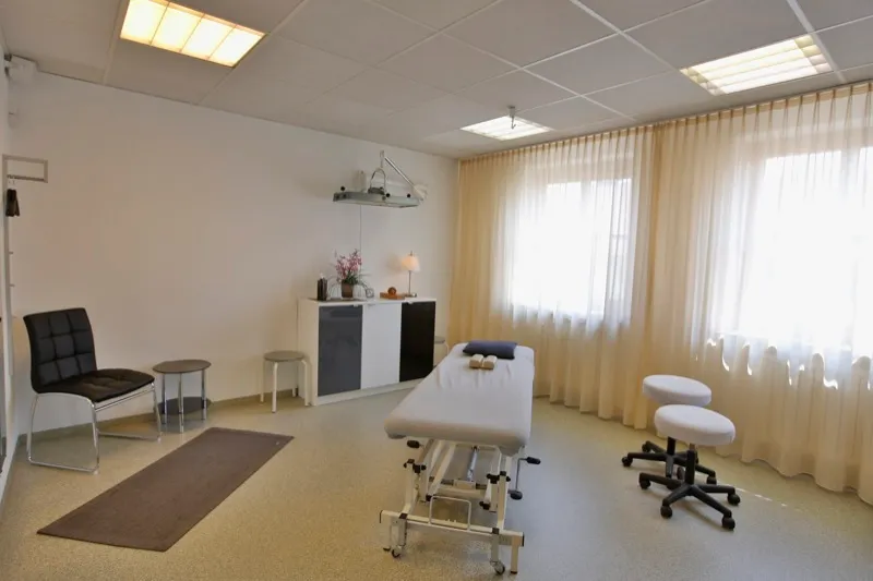 Behandlungsraum mit Liege, Wartestuhl und Ablage